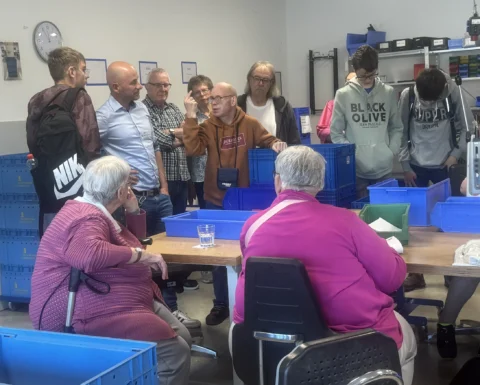 Ein Mann erklärt anderen Menschen, wie in der Werkstatt gearbeitet wird.