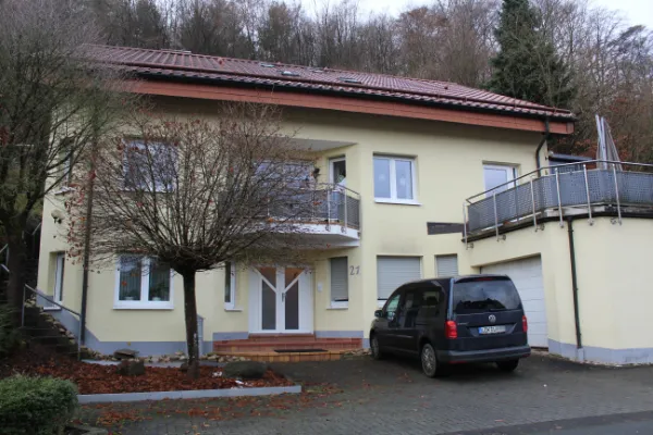 Modernes Wohnhaus in den Thalen mit Balkon, Garage und Van vor Waldhang.