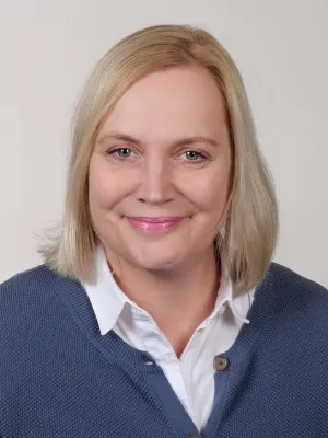Porträt von Anje Rau, blonde Frau im Business-Outfit, professionelles Foto, freundliches Lächeln.