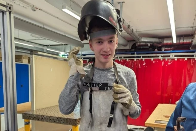 Junger Mensch mit Unterstützungsbedarf im Berufsbildungsbereich der Lebenshilfe Dillenburg beim Schweißen – praxisnahe Qualifizierung in der Metallwerkstatt mit Schutzkleidung.