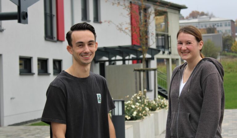 Tim Gerks und Maren Schmidt starten Ausbildung bei Lebenshilfe Dillenburg vor modernem Gebäude.