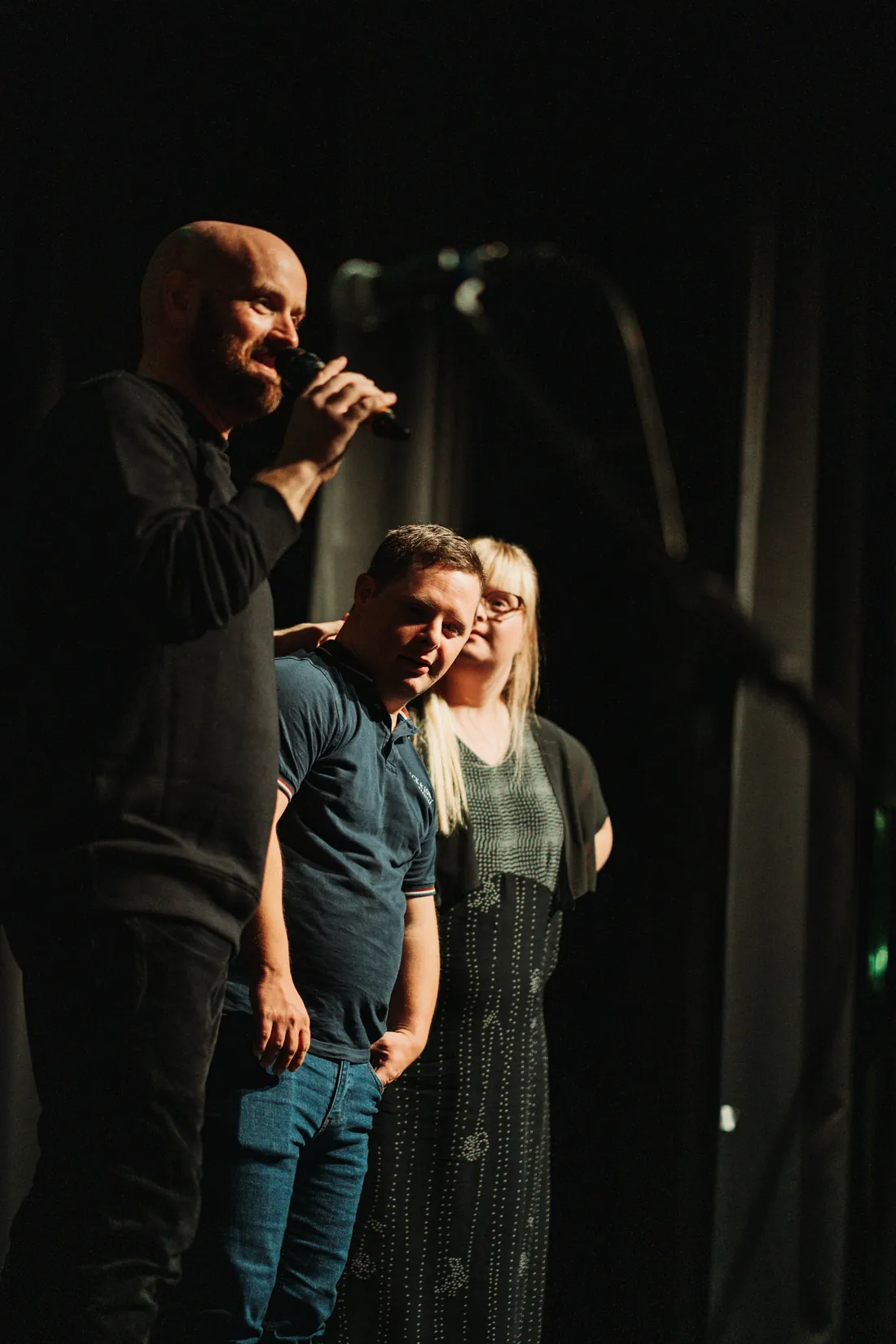 Mann spricht ins Mikrofon, zwei Personen daneben auf Bühne beim Scheunen-Slam Herborn.