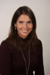 Porträt von Cornelia Holtfoth, professionelle Businessfotografie mit freundlichem Lächeln vor hellem Hintergrund.