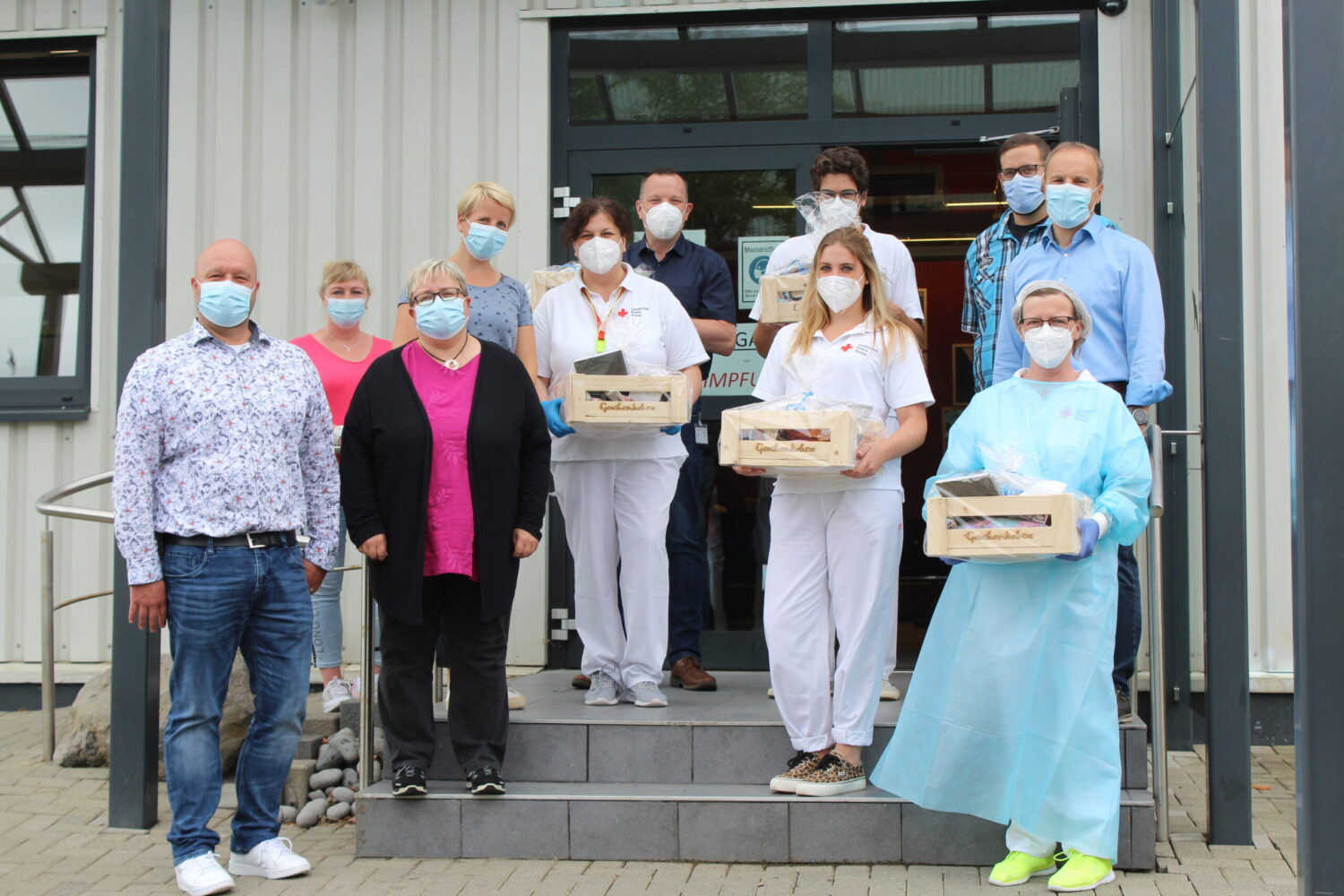 Lebenshilfe Dillenburg überreicht Genusskörbe an DRK-Impfteam vor Impfzentrum, Gruppenfoto mit Masken