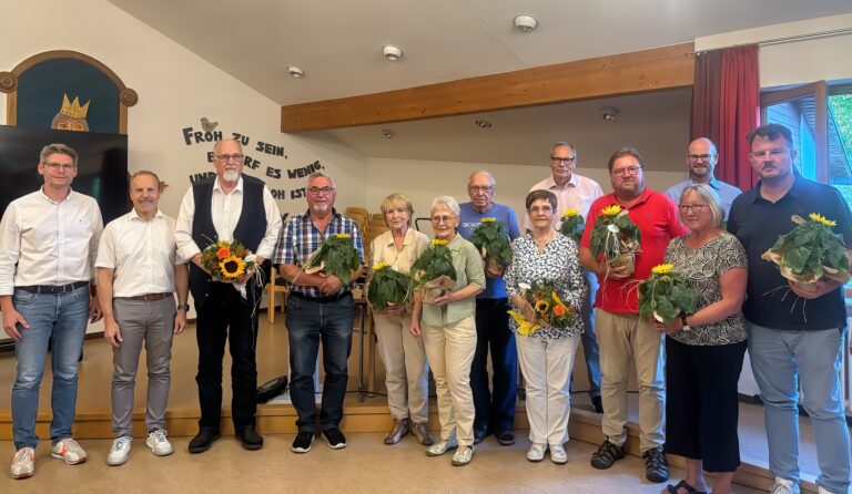 Ehrungen im Jubiläumsjahr: Gruppe mit Blumen und Sonnenblumen im Gemeinschaftsraum.