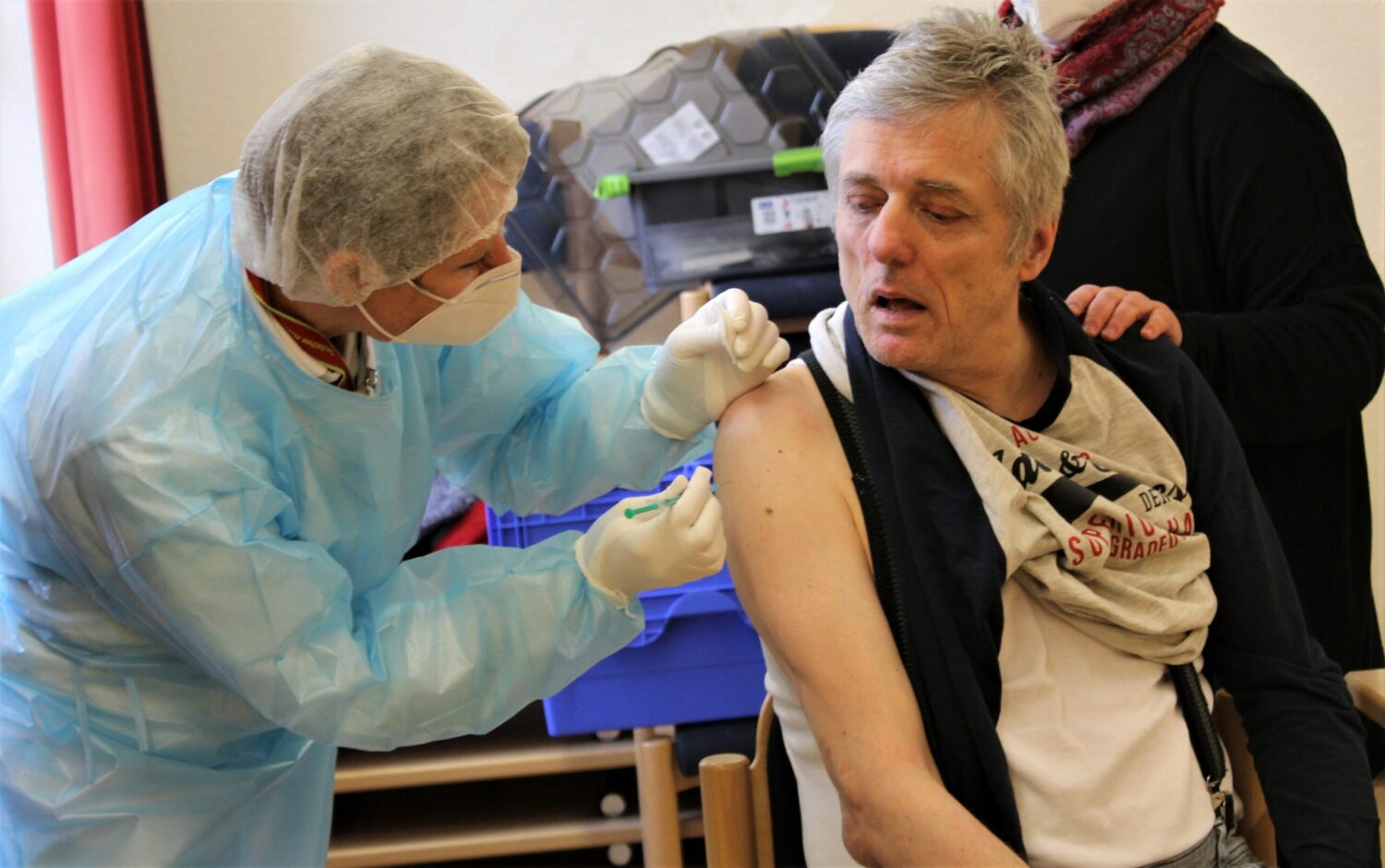 Pflegekraft impft Bewohner im Wohnheim Manderbach gegen Corona, kurzer Pieks in den Oberarm.