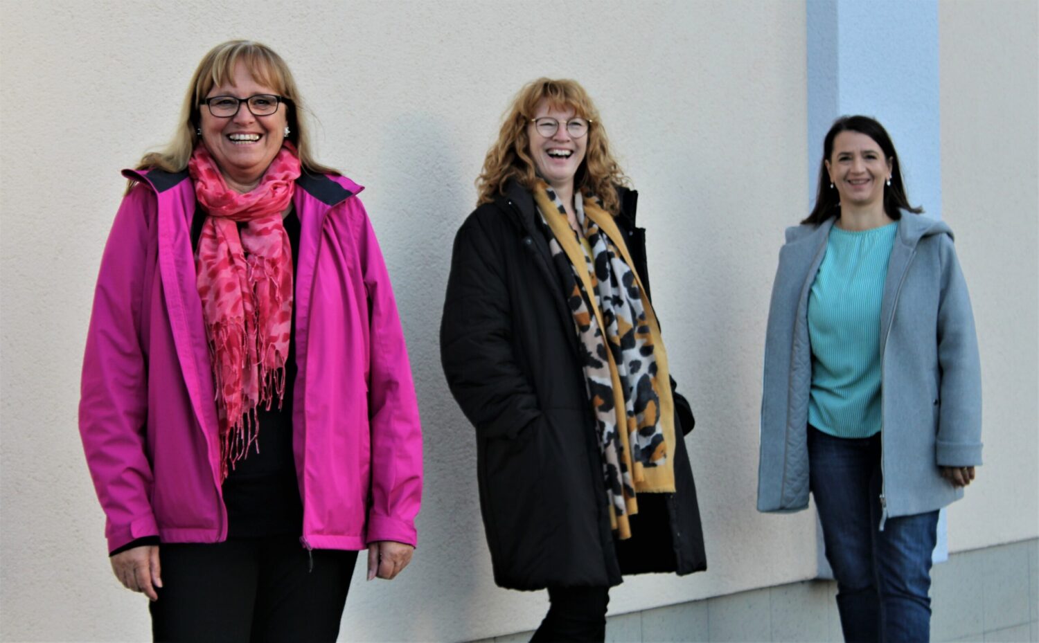 FeD-Team Lebenshilfe Dillenburg: Drei Kolleginnen lächeln im Freien vor heller Wand.