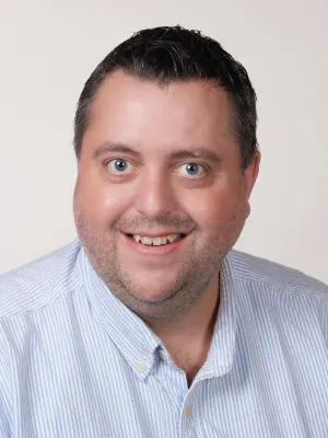 Porträt von Florian Bär, freundlicher Mann mit blauem Hemd, professionelles Business-Headshot.