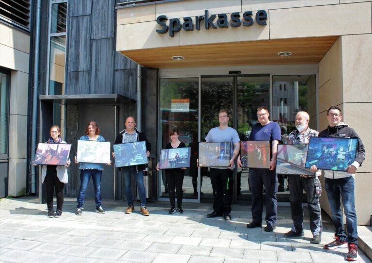 Gruppe zeigt Fotoausstellung-Werke vor der Sparkasse, lokale Künstler präsentieren gerahmte Fotografien.