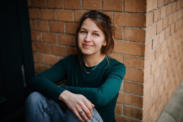 Porträt der Fotografin Sandy Klein sitzend vor Backsteinwand, Lebenshilfe Dillenburg Kalender-Shooting.