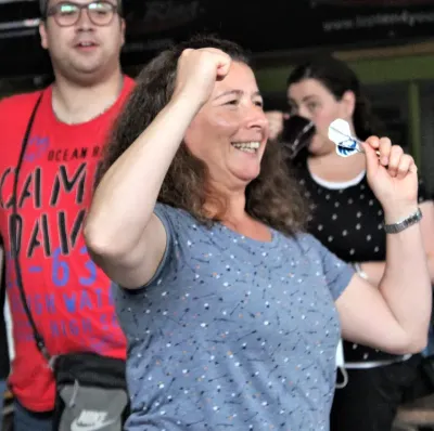 Frau jubelt nach perfektem Dartwurf beim Darts spielen im Freizeitclub.