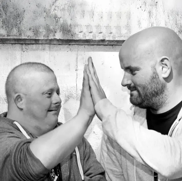 Inklusion und Freundschaft: Zwei Männer geben sich ein High-Five und lächeln.