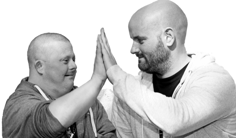 Zwei Männer geben sich lachend ein High-Five – Inklusion, Freundschaft und Teamwork in Schwarzweiß.