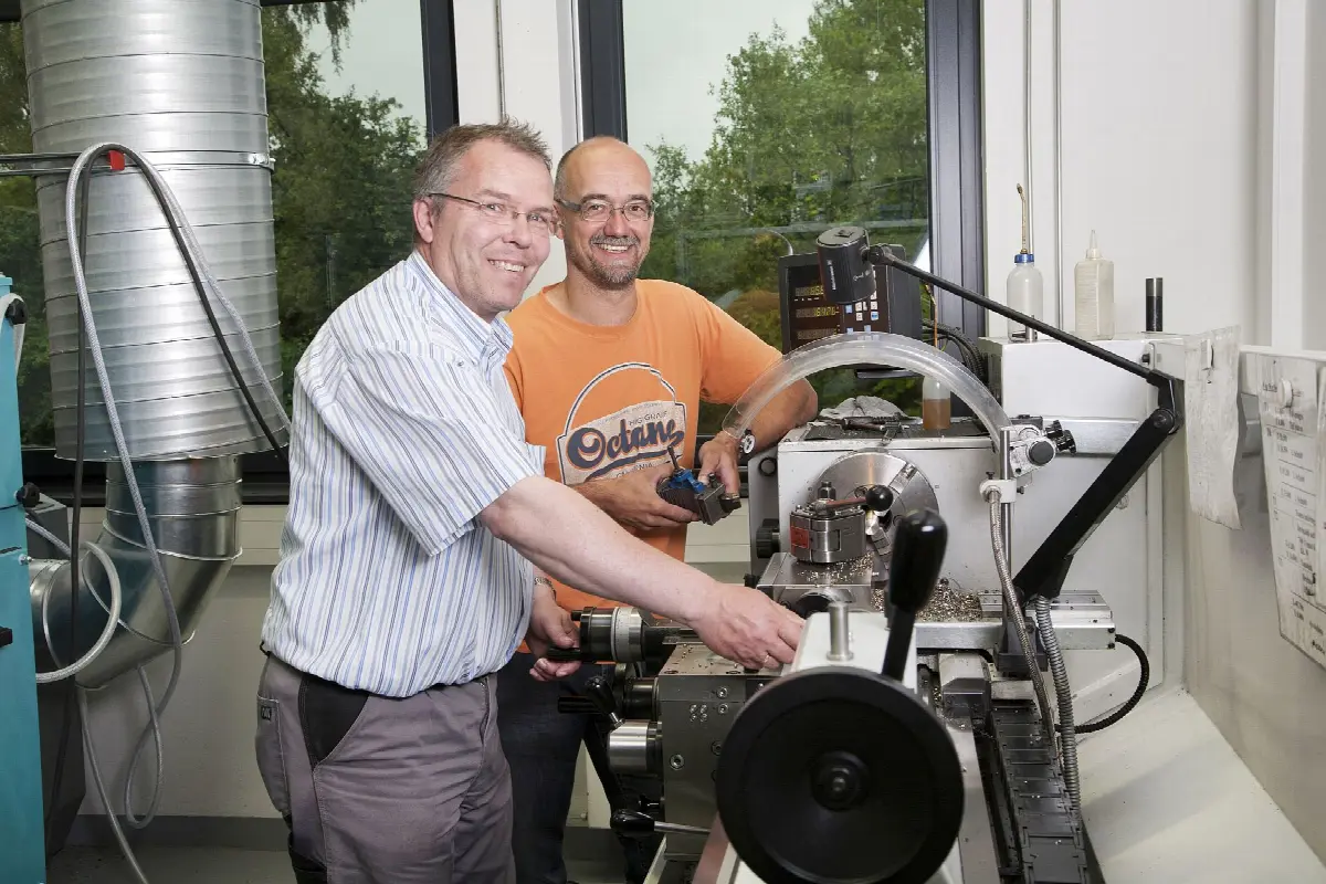 Zwei Mitarbeiter arbeiten an einer Drehmaschine in der Metallwerkstatt der Lebenshilfe Dillenburg.