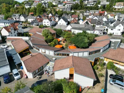 Luftaufnahme Kinderzentrum mit ringförmigem Gebäudekomplex und Innenhof im europäischen Dorf.