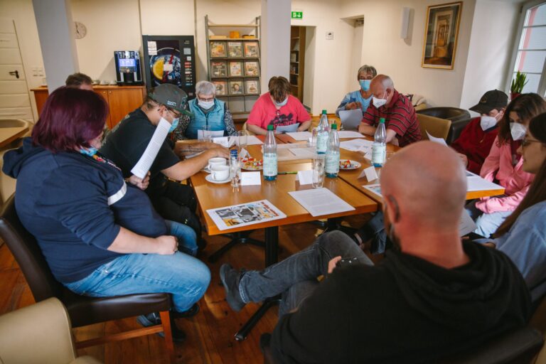Lesestunde der Lebenshilfe Dillenburg: Gruppe liest und diskutiert gemeinsam am Tisch mit Masken.