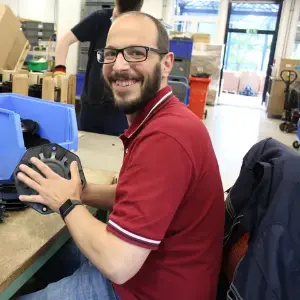 Lächelnder Mann montiert Bauteile in Werkstatt am Arbeitsplatz, Produktion und Montage.