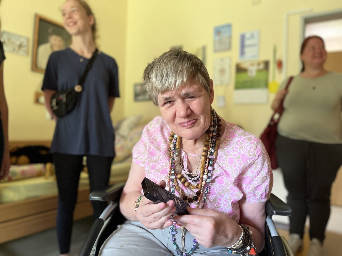 Marlene Schleidt im Rollstuhl zeigt stolz ihr eigenes Zimmer und hält ein Geschenk.