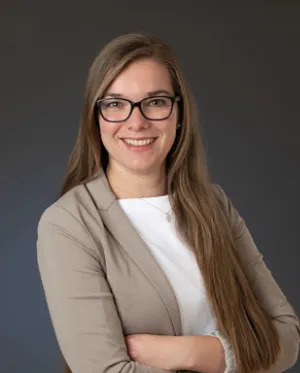 Professionelles Business-Porträt von Michelle Duschek mit Brille, Blazer und freundlichem Lächeln.