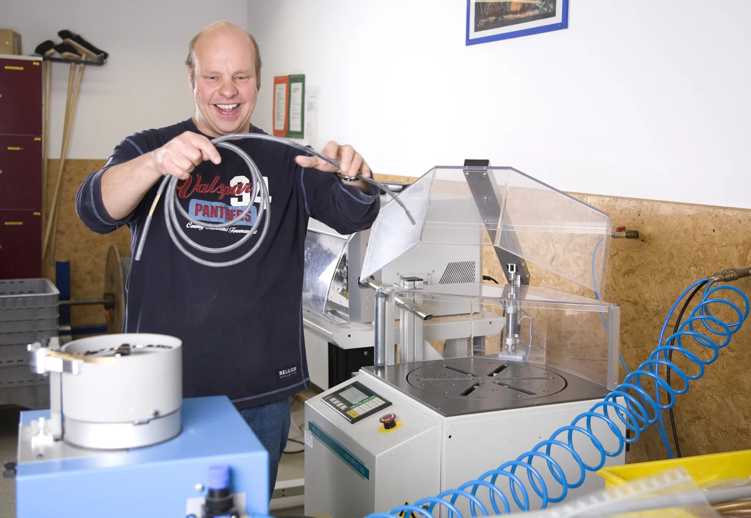 Lächelnder Mitarbeiter konfektioniert Kabel an Industriemaschine in Werkstatt der Lebenshilfe Dillenburg.