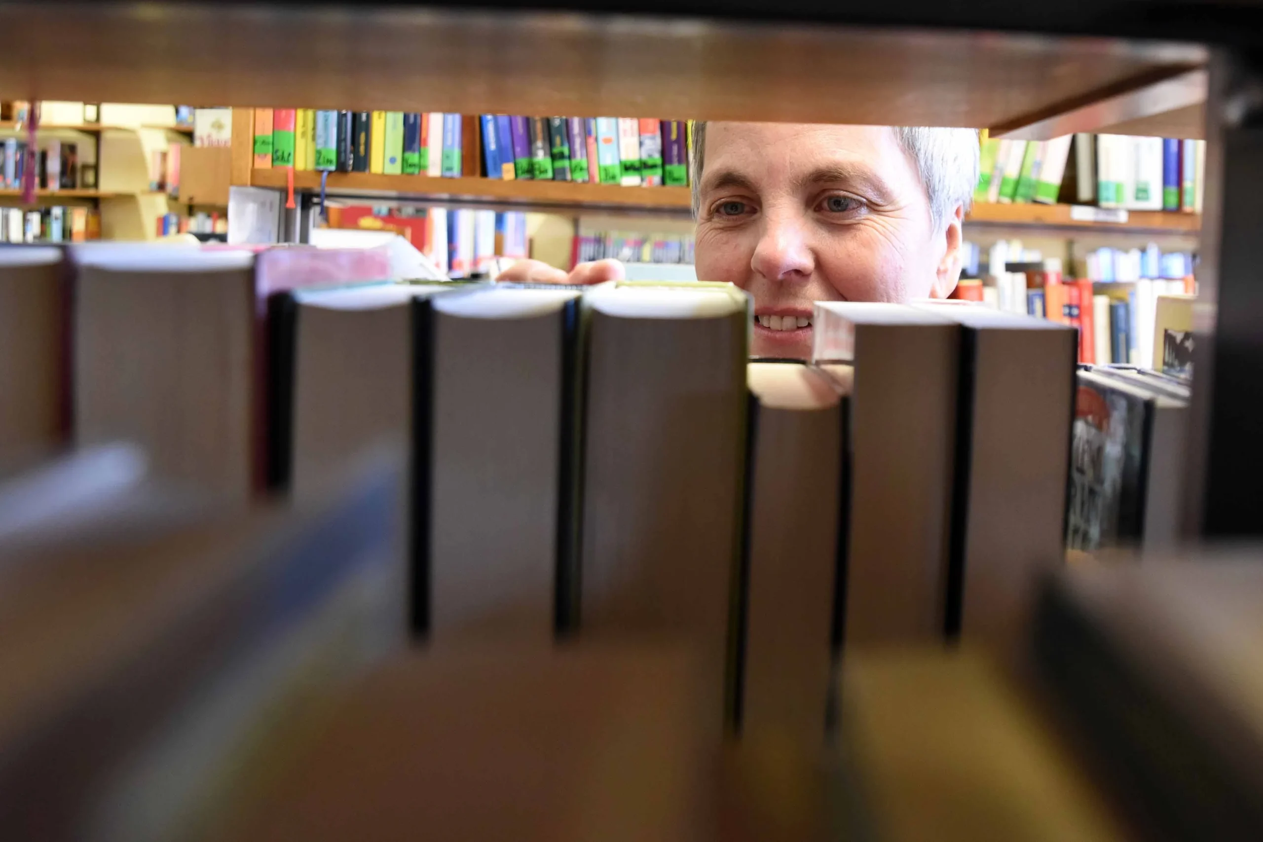 Frau wählt Bücher im Regal der Stadtbücherei Haiger aus.