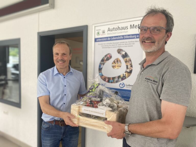 Dirk Botzon überreicht Achim Metz bei Autohaus Metz Dillenburg einen Präsentkorb.