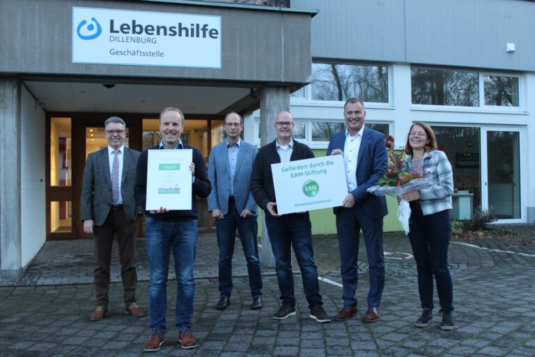 Gruppenfoto bei Lebenshilfe Dillenburg: Preisübergabe 10.000 Euro, EAM-Stiftung und Blumenstrauß.