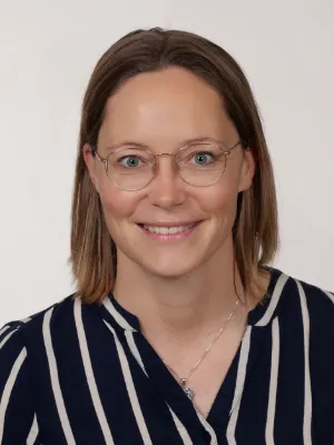 Lächelnde Frau mit Brille im Business-Porträt vor hellem Studiohintergrund