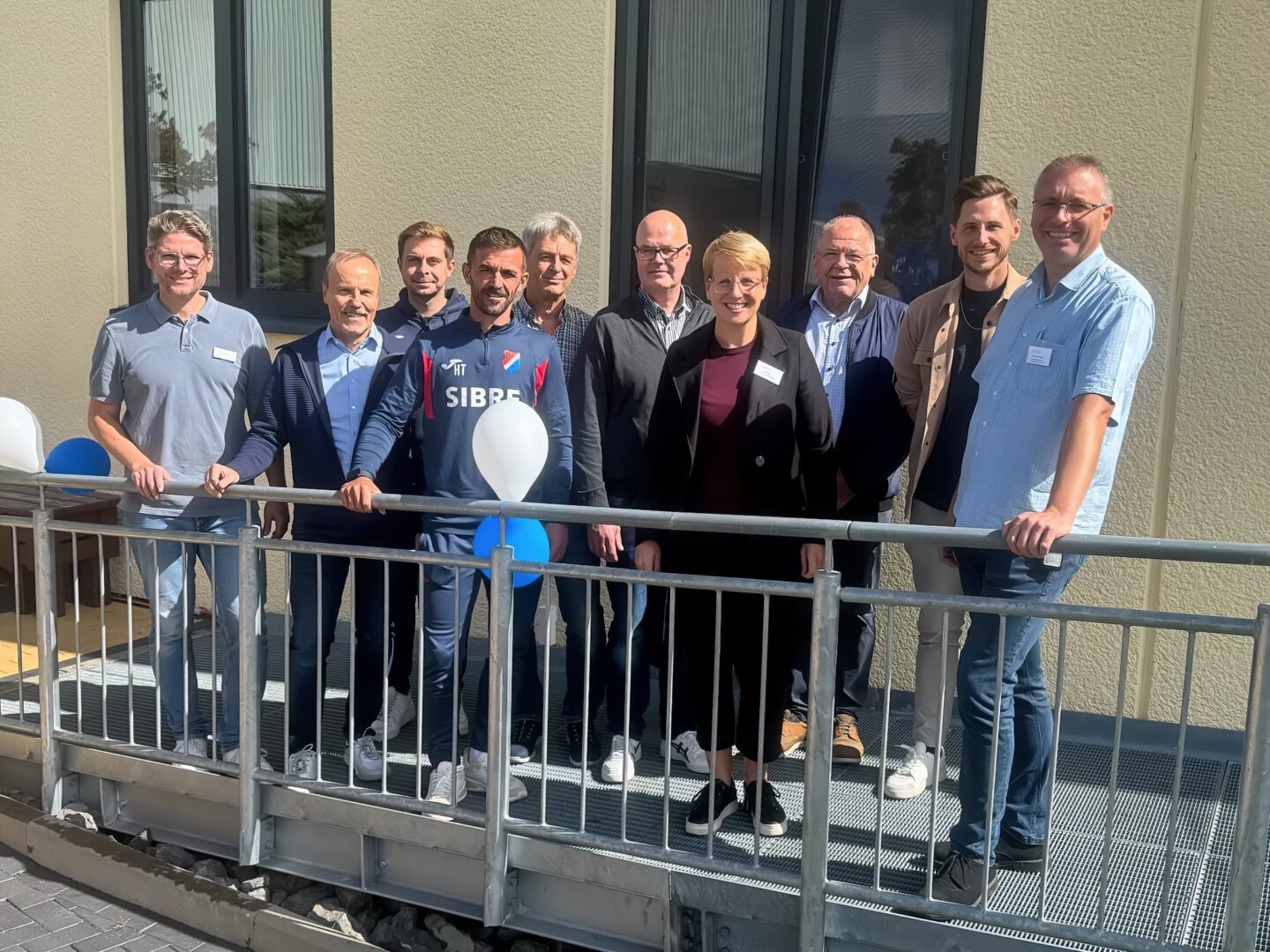 Gruppenfoto beim Event: TSV-Trainer und Lebenshilfe-Team auf Rampe mit Ballons.