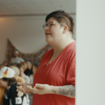 Mann im roten Shirt spricht engagiert vor Publikum bei Deutschland-Fan-Event in Halle.