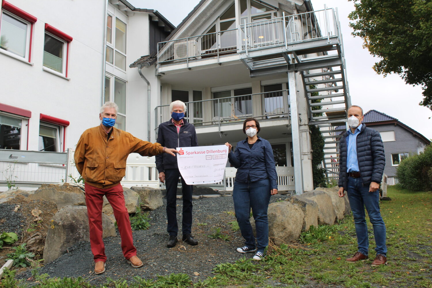 Scheckübergabe am Lebenshilfe-Wohnheim Simmersbach: vier Maskierte präsentieren symbolischen Sparkasse-Dillenburg-Scheck.