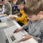 Zwei Schüler montieren konzentriert ein Technikprojekt im Werkraum einer Schule.