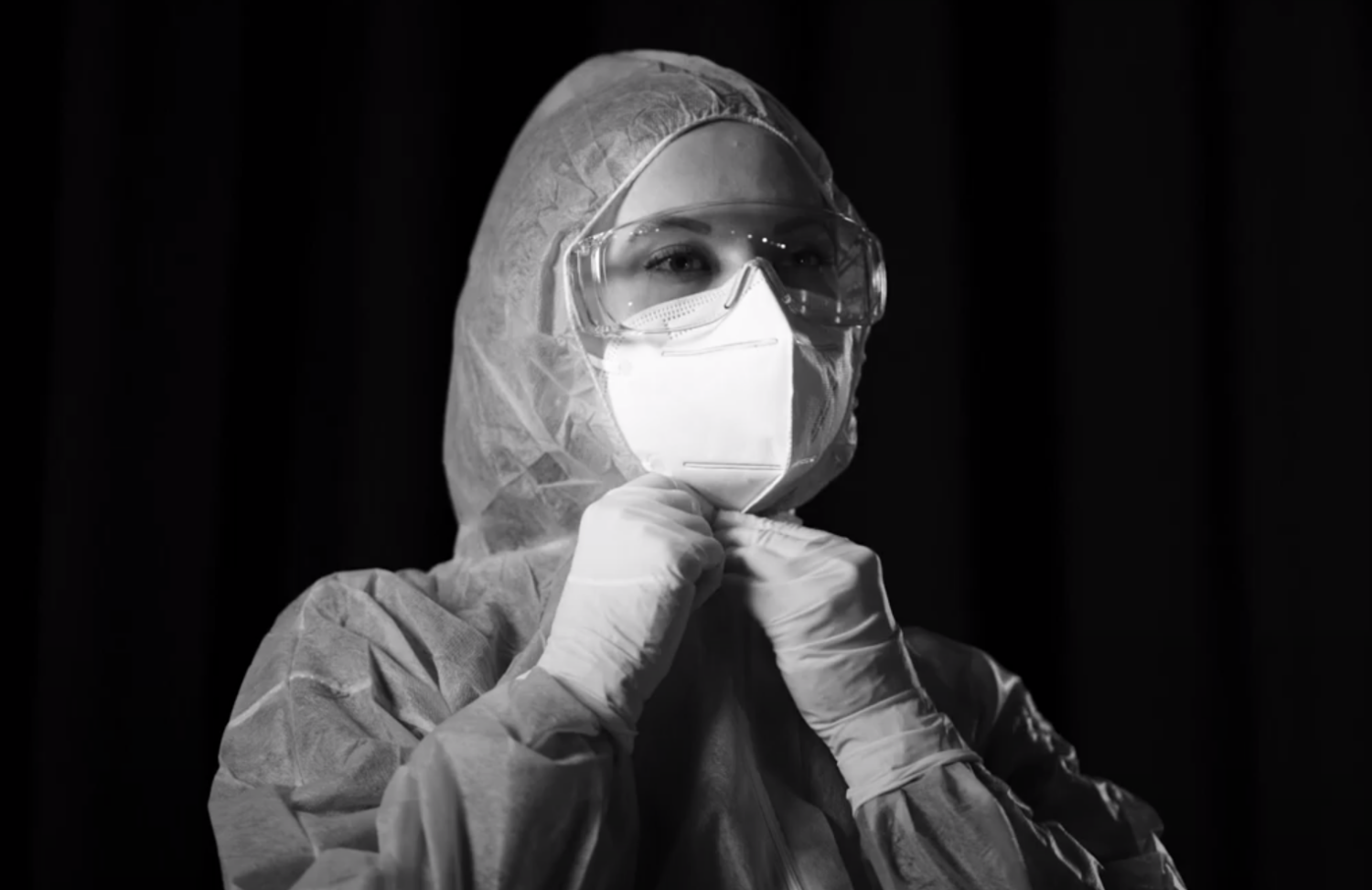 Medizinisches Personal im Schutzanzug mit Schutzbrille und FFP2-Maske, bereitet sich vor.