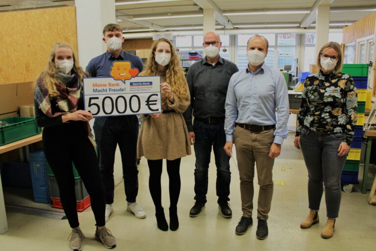 Sparda-Bank überreicht 5.000-Euro-Scheck im Workshop an Lars Lückoff und Dirk Botzon.