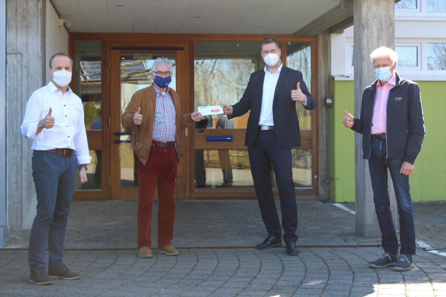Sparda-Bank überreicht Spende an Lebenshilfe Stiftung, vier Männer mit Masken vor Eingang.
