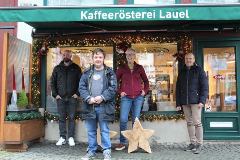 Spendenübergabe vor Kaffeerösterei Lauel Ahrweiler: vier Personen mit 1000-Euro-Spende, Weihnachtsdeko.