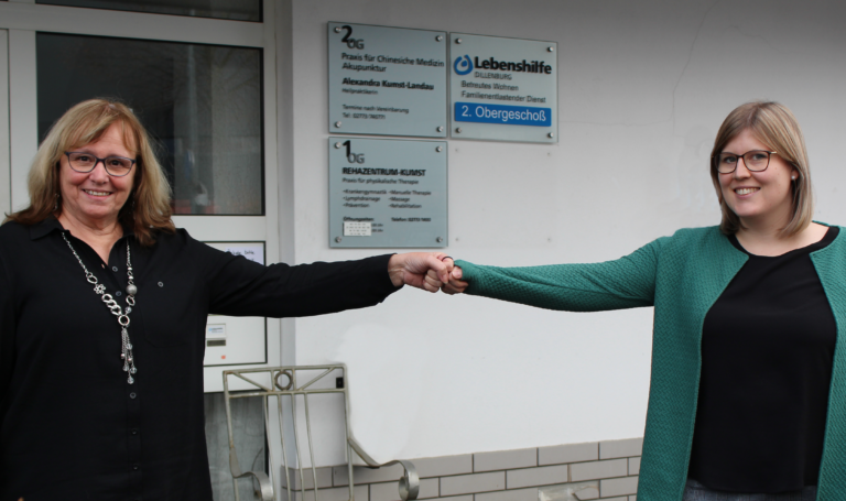 Anita Groskurt übergibt bei Lebenshilfe Dillenburg an Isabel Zint, beide lächeln.