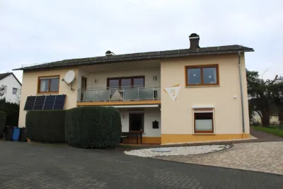 Stationär begleitetes Wohnen: Zweistöckiges Wohnhaus mit Balkon, Solarpanels und Einfahrt.