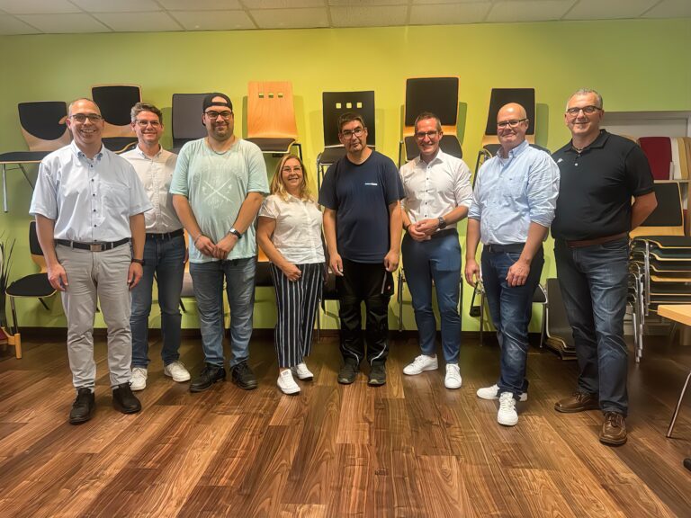 Acht Workshop-Teilnehmende posieren zum Teamfoto zur beruflichen Inklusion in hellem Raum.