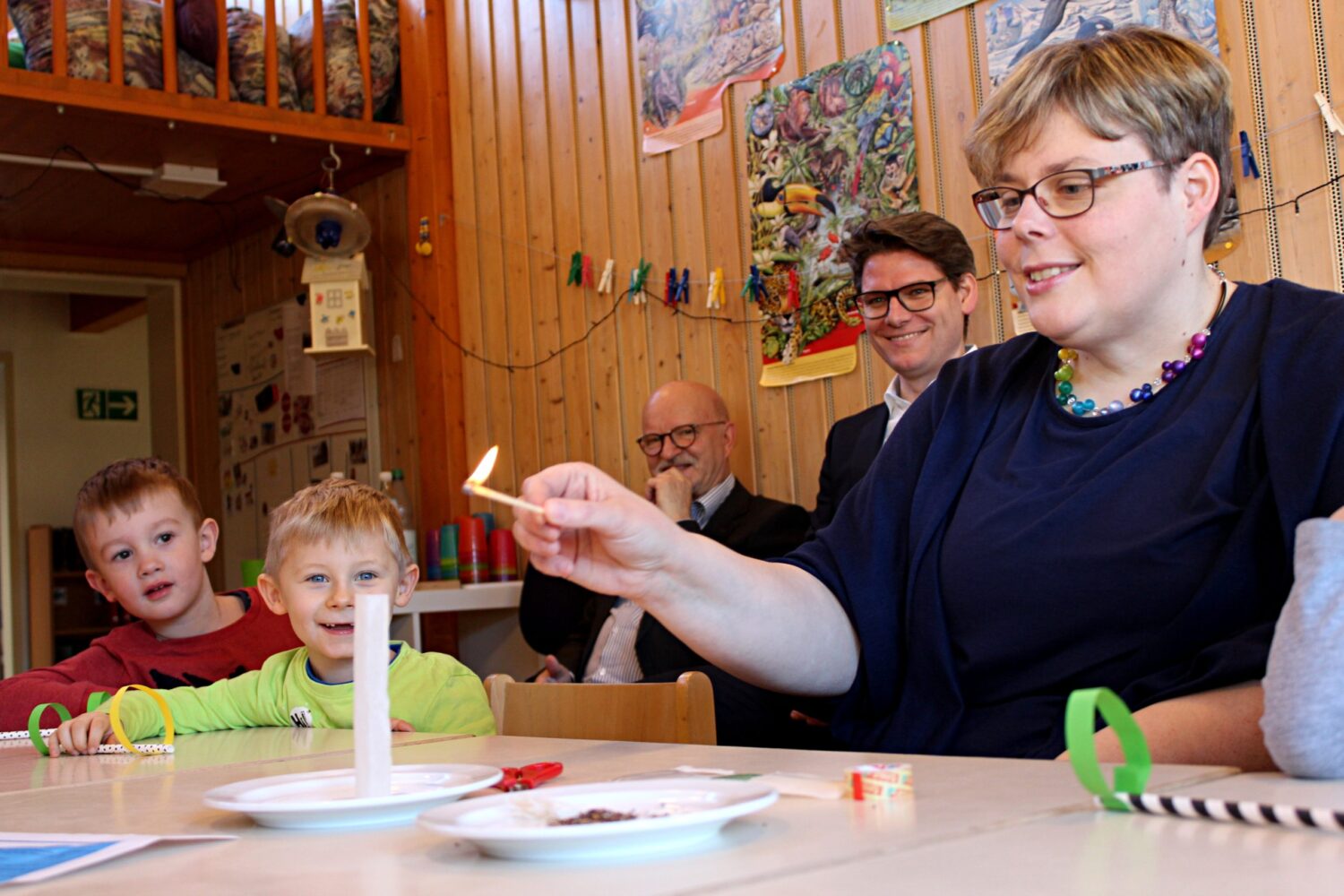 Erzieherin zündet Teebeutel-Rakete an, Kinder staunen beim Experiment im Kindergarten.