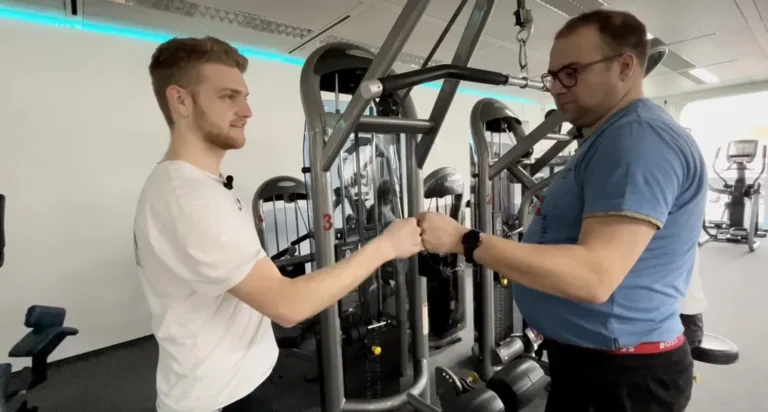 Personal Trainer gibt älterem Mann im modernen Fitnessstudio motivierenden Fauststoß