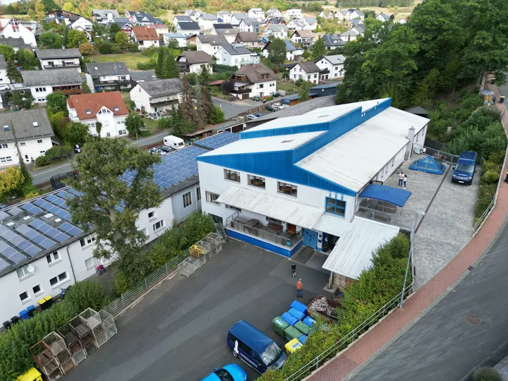 Drohnenaufnahme einer modernen Werkstatt in Eibelshausen mit markantem blau-weißem Dach