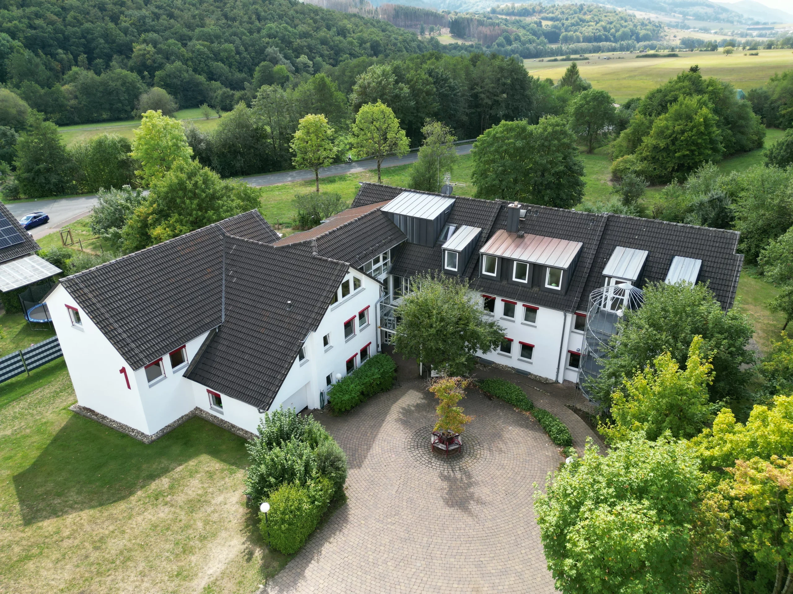 Luftaufnahme eines modernen Wohnheims in Simmersbach mit Innenhof und grüner Landschaft.